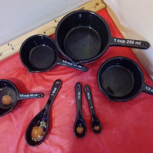 Può includere: Un set di misurini e cucchiai in ceramica nera. Il set include misurini da 1 tazza (250 ml), 1/2 tazza (125 ml), 1/3 tazza e 1/4 tazza (60 ml). I cucchiai sono da 1 cucchiaio, 1/2 cucchiaino e 1/4 cucchiaino. Ogni pezzo ha un design a zucca.