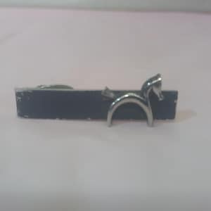 May include: A silver tie clip with a horse design. The clip is attached to a black bar.