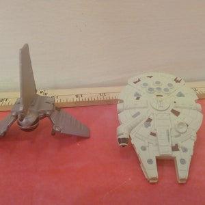 May include: Two Star Wars toy spaceships. A gray TIE fighter and a white Millennium Falcon.