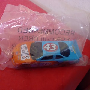 May include: A blue and orange toy race car with the number 43 on the side and the word "Wheaties" on the side. The car is in a clear plastic bag with the words "For Children Recommended" printed on the bag.