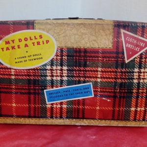 May include: A red and green tartan suitcase with the text "My Dolls Take A Trip" and "Cloth-Like Dresses" on it. The suitcase is for a dollhouse and includes 4 stand-up dolls made of Tekwood, dresses, hats, coats, and scissors to cut them out.