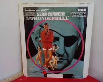 May include: A vintage RCA SelectaVision VideoDisc of the James Bond film "Thunderball" starring Sean Connery. The cover features a close-up of Connery's character in a red wetsuit holding a spear gun, with a woman in a bikini in the background. The cover also features a close-up of a man's face with an eyepatch.