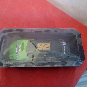 May include: A black and green toy race car with the number 92 and the name Stacy Compton on the side. The car is in a plastic package.