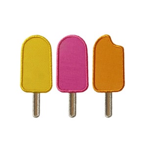 May include: Three embroidered felt popsicle patches in yellow, pink, and orange. The popsicles are all the same size and shape, and they have a simple, cartoonish design.