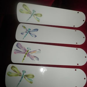 May include: Four white ceiling fan blades with painted dragonfly designs. Each blade features a different dragonfly with varying colors, including green, blue, purple, and pink.