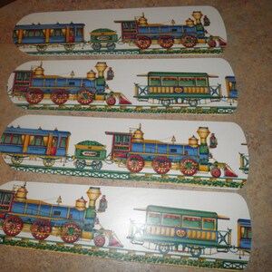 May include: Four white ceiling fan blades with a blue and yellow train design. The train is a steam engine with a passenger car and a boxcar. The train is on a track with green grass and brown dirt.