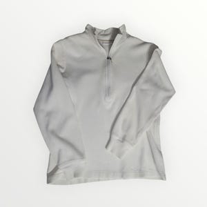 May include: A white, long-sleeved sweatshirt with a quarter-zip closure. The collar is ribbed, and the cuffs are also ribbed. The sweatshirt is made of a soft material and is suitable for casual wear.