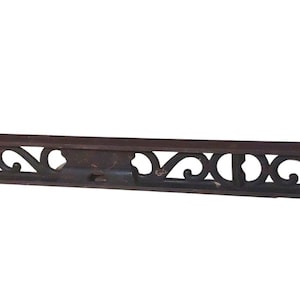 May include: A vintage cast iron level with an ornate design. The level is dark brown and has a decorative pattern along the top and bottom edges.