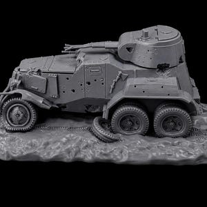 May include: A gray scale model of a damaged six-wheeled armored vehicle featuring a turret with a mounted cannon, multiple bullet hole indentations on the side panels, and a detached tire resting on the ground beside the rear wheels.