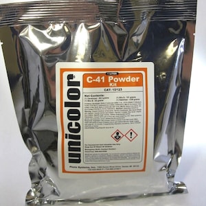 May include: A silver pouch containing a C-41 Powder Kit for developing photographic film. The pouch is labeled with the brand name "unicolor" and the product name "C-41 Powder Kit". The pouch also includes the product's catalog number, "CAT: 10123", and a list of the kit's contents, including the developer, blix, and stabilizer.