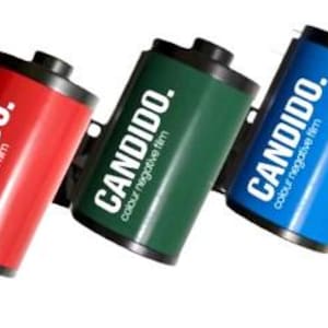 May include: Three film canisters, one red, one green, and one blue, with the word "CANDIDO." and the text "colour negative film" printed on each.