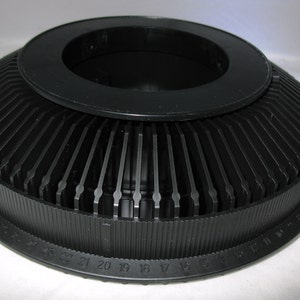 May include: Black plastic slide projector carousel with numbered slots for 80 slides. The carousel has a central opening for the projector spindle.