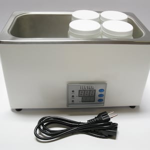 May include: White laboratory water bath with a digital temperature control panel displaying "88.8" and a power cord. Four white plastic containers are inside the bath.