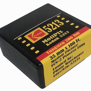 May include: A black plastic container with a yellow label. The label reads "Kodak 5213- MotiPix Kodak 5213 Tungsten 200 ISO 35 mm x 100 Ft. Motion Picture ECN-2 Process Film Loaded by: Photo Warehouse Cat#926-52131".