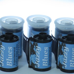 May include: Three rolls of 35mm color print film with blue and white labels. The labels read "Jazzy Blues Experimental Color Print Film".