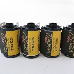 May include: Four rolls of Kodak Vision2 250D/5205 35mm colour negative film. Each canister features a yellow and black label with the text Kodak Vision2, Colour Negative Film, 250D/5205, and 35mm x 36 Exp. The film canisters have black plastic ends.