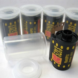 May include: Five rolls of 35mm Kodak 5213 film, four are in their original plastic containers and one is unwrapped. The film is black with yellow and red text that reads "Kodak 5213" and "Kodak" with a red Kodak logo. The film also has the text "Modipix" and "Kodak 5213" in yellow.