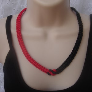 May include: A black and red braided necklace. The necklace is made of two strands of cord, one black and one red, that are braided together.