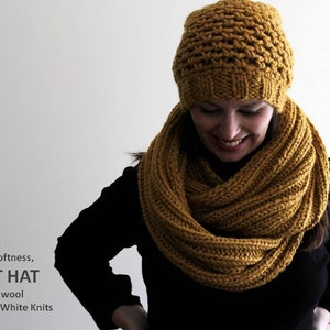 May include: A cozy, mustard yellow knit hat and matching infinity scarf. The hat has a textured stitch pattern and the scarf is a simple knit. The text "Cozy softness, KNIT HAT 50% wool By, Winter White Knits" is visible at the bottom of the image.