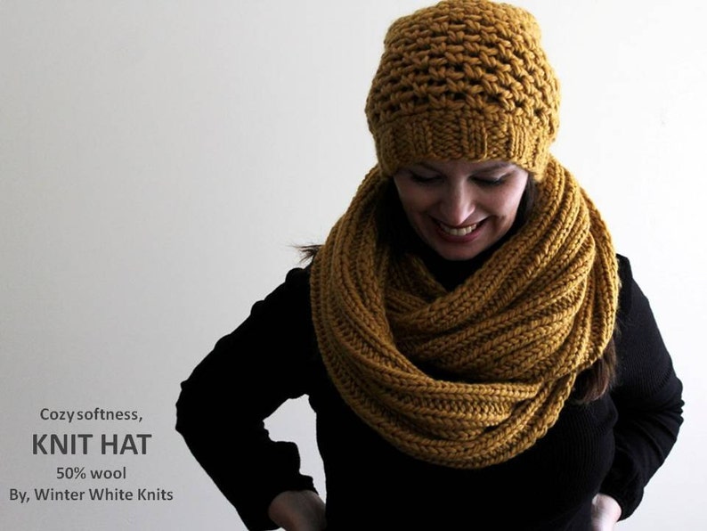 May include: A cozy, mustard yellow knit hat and matching infinity scarf. The hat has a textured stitch pattern and the scarf is a simple knit. The text "Cozy softness, KNIT HAT 50% wool By, Winter White Knits" is visible at the bottom of the image.