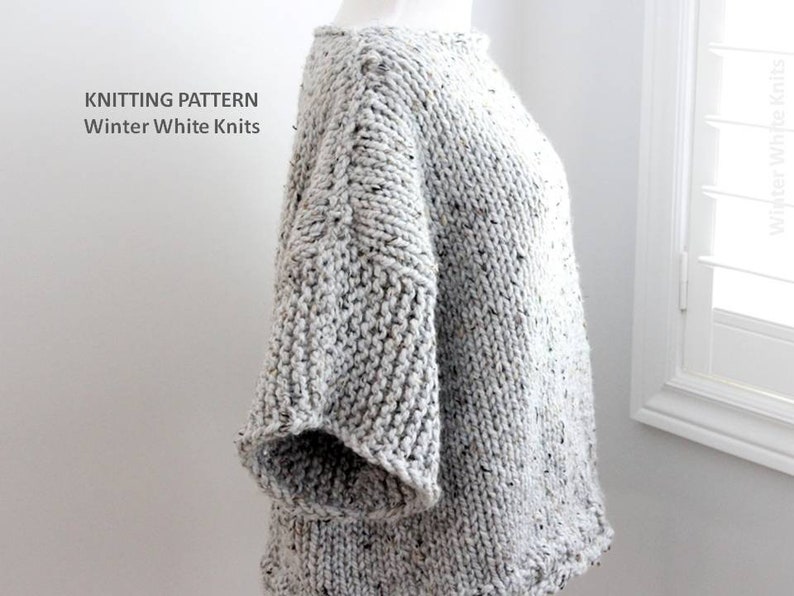 May include: A gray knitted sweater with a speckled pattern. The sweater has a round neckline and short sleeves. The sweater is shown on a white mannequin.