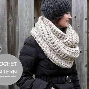 May include: A crocheted infinity scarf in a light beige color. The scarf is worn by a person wearing a black jacket and a gray beanie. The text "CROCHET PATTERN By, Winter White Knits" is visible in the image.