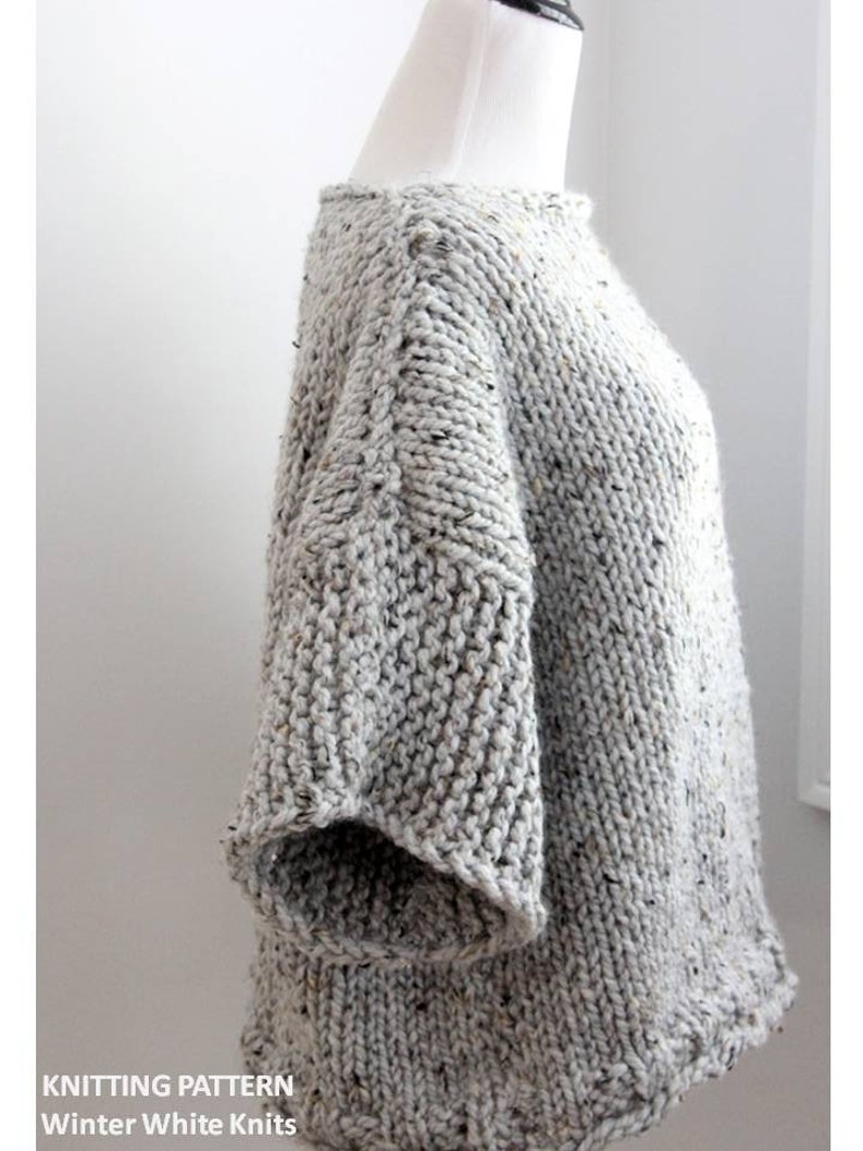 May include: A gray knitted sweater with a speckled pattern. The sweater has a round neckline and long sleeves. The sweater is on a white mannequin.