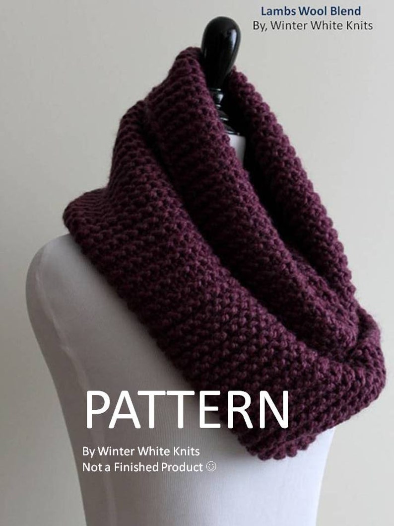 May include: A deep purple chunky knit infinity scarf draped on a mannequin. The text reads: Lambs Wool Blend By, Winter White Knits, PATTERN By Winter White Knits Not a Finished Product.
