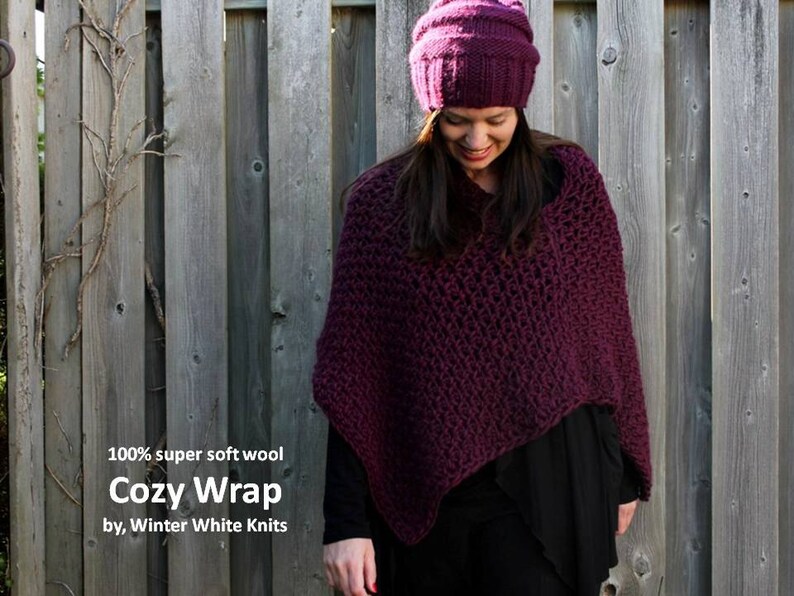May include: A close-up of a woman wearing a deep purple knitted wrap and a matching beanie. The wrap is made of 100% super soft wool and is called "Cozy Wrap" by Winter White Knits.