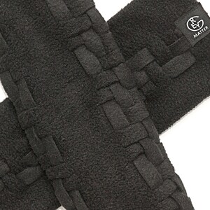 May include: Two black fleece arm warmers with a woven design. The arm warmers have a black label with the text "RE MATTER" on them.