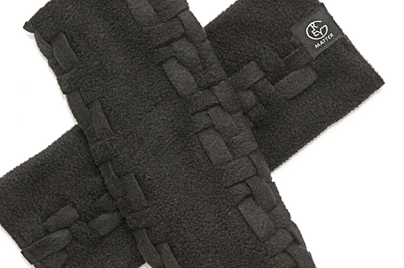 May include: Two black fleece arm warmers with a woven design. The arm warmers have a black label with the text "RE MATTER" on them.
