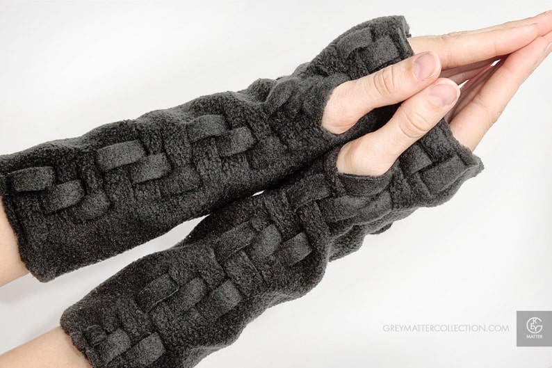 May include: A pair of gray fingerless gloves with a woven pattern. The gloves have a finger hole opening on each glove.