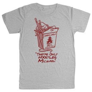 May include: A light gray t-shirt featuring a red graphic of a Chinese food takeout box with noodles and chopsticks. The text on the box reads "SANTA CARLA NO. 1 CHINESE FOOD". Below the box, the text reads "THEY'RE ONLY NOODLES MICHAEL".