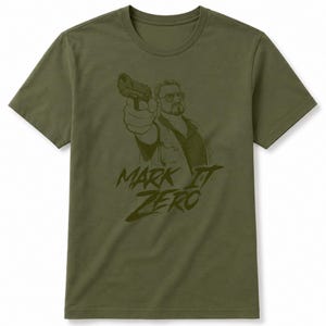 Może przedstawiać: Oliwkowozielony t-shirt z krótkim rękawem z ciemnozieloną grafiką przedstawiającą osobę w okularach trzymającą pistolet. Pod ilustracją znajduje się napis "MARK IT ZERO" wykonany pogrubioną, stylizowaną ciemnozieloną czcionką.