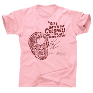 Puede incluir: Camiseta rosa claro con una ilustración de dibujos animados de un hombre con gafas y el texto "OH I HATED THE COLONEL! WITH HIS WEE BEADY EYES!!" La camiseta también incluye la firma "Stuart Macfarlane" y "Proud Scotsman."