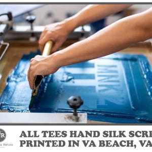 May include: A person using a squeegee to apply blue ink to a screen printing frame. The text "MNK" is visible on the screen. The image also includes the text "ALL TEES HAND SILK SCREEN PRINTED IN VA BEACH, VA!" and the Radical & Retro logo.