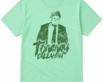 Puede incluir: Una camiseta de manga corta en color verde menta claro con un estampado gráfico desgastado en verde oscuro de un hombre con traje y corbata. Debajo de la figura, el texto TOMMY CALLAHAN está impreso en una fuente verde oscuro texturizada.