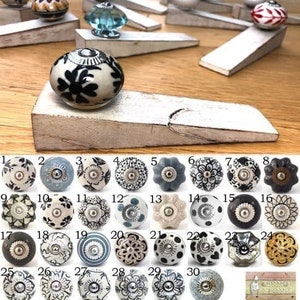 May include: A set of 30 white ceramic door knobs with various black and blue patterns. The knobs are displayed on a white wooden surface with the text "de Bobbles" in the bottom right corner.