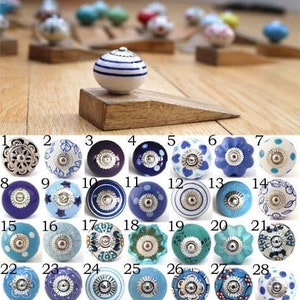 May include: Twenty-eight ceramic knobs in various blue and white patterns. The knobs have a silver metal accent in the centre.