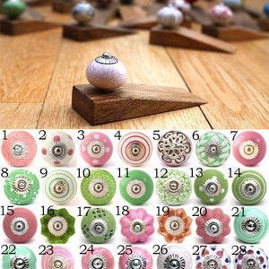 May include: Assortment of 28 ceramic knobs in various colours and patterns, including pink, green, and white. The knobs are arranged in rows and numbered 1 through 28.