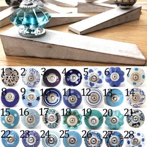 May include: Assortment of 28 ceramic knobs with blue and white designs. The knobs have a silver metal base and are arranged in rows of 4.