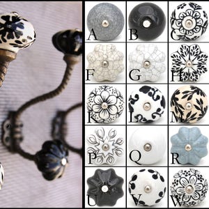 May include: A set of three black metal hooks with white ceramic knobs. The knobs feature a variety of black and white patterns, including floral, geometric, and polka dot designs. The hooks are perfect for hanging coats, hats, or towels.