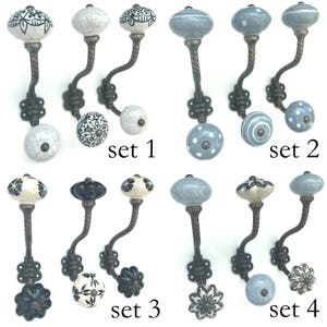 May include: A selection of decorative wall hooks with ceramic knobs. The knobs display floral and geometric patterns in white, black, and blue. The metal stems have a twisted design and are attached to decorative mounting plates. The sets are labelled 1, 2, 3, and 4.