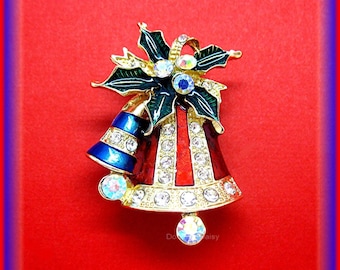 May include: A gold-tone Christmas bell brooch with red and blue enamel and clear rhinestones. The bell is topped with a green holly leaf and berry design.