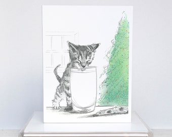 May include: A greeting card featuring a pencil sketch of a kitten drinking milk from a glass. A Christmas tree is in the background. A stack of white cards is in the foreground.