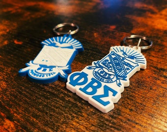 May include: Two white and blue keychains with the Greek letters Phi Beta Sigma and the words "Founded 1914".