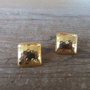May include: A pair of gold-toned square earrings with a hammered texture.