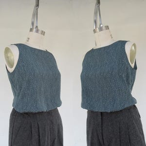 May include: A sleeveless top with a blue and white striped pattern. The top is made of a silky fabric and has a scoop neckline. The top is being displayed on a mannequin.