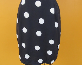 May include: A black skirt with white polka dots. The skirt is knee-length and has a fitted silhouette.