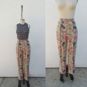May include: High-waisted pants with a floral print in shades of pink, yellow, and blue on a beige background. The pants have a wide leg and are made of a lightweight fabric.